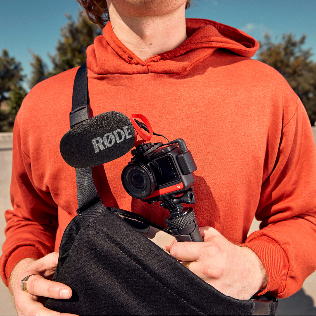 Skater wearing orange jumper and sling bag  holding camera with VideoMicro II mounted on