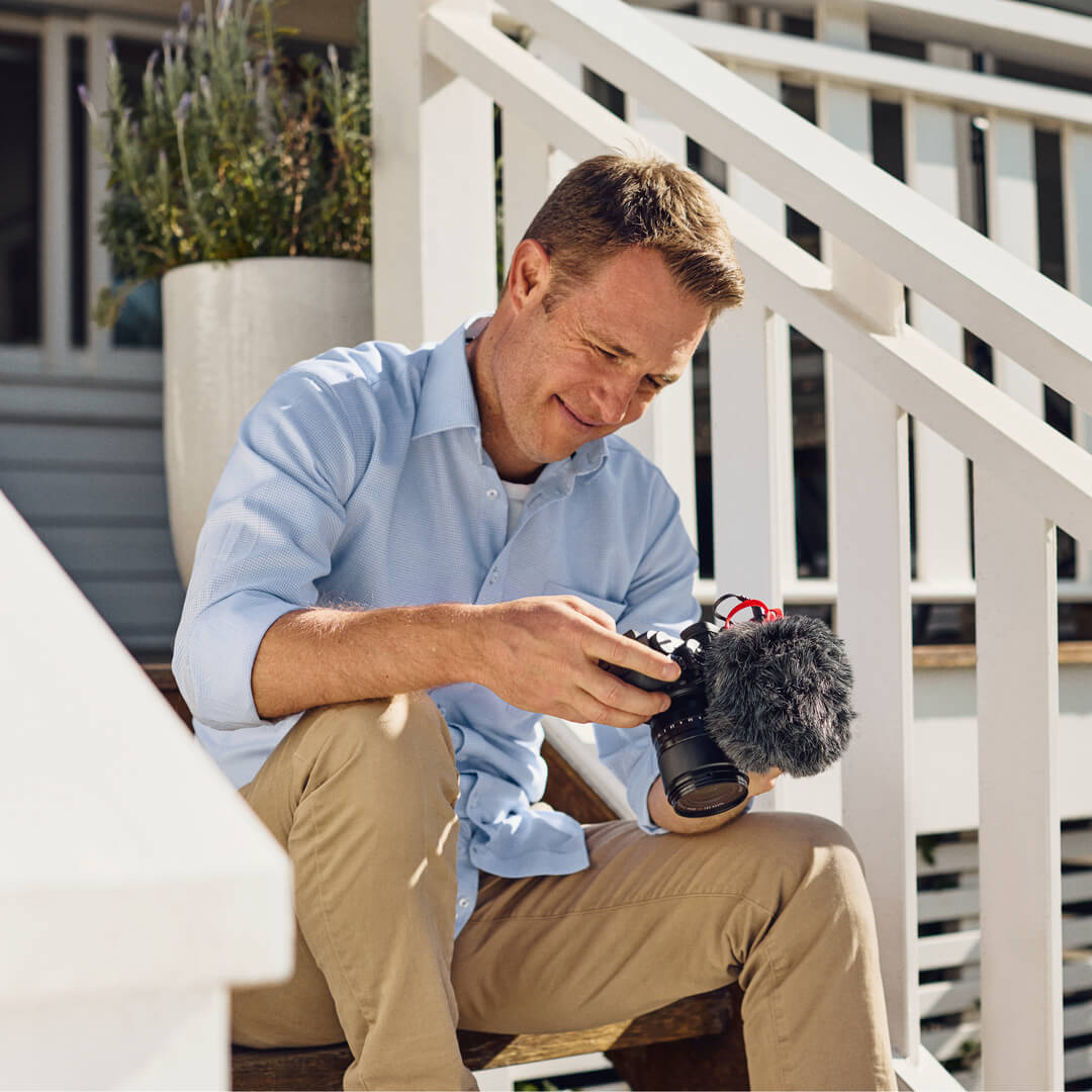 Man sitting on stairs holding camera with VideoMicro II mounted on