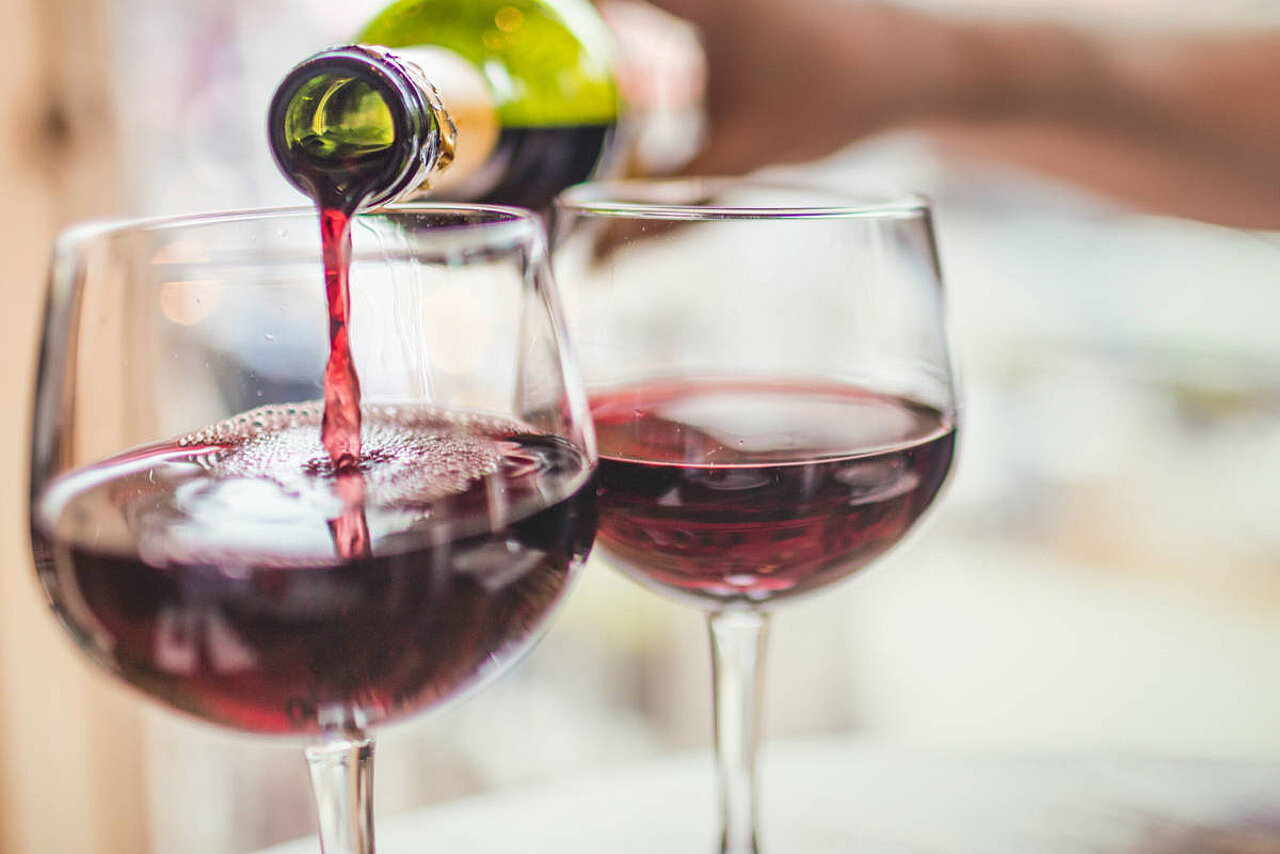 Zwei Weingläser, in denen Wein eingegossen wird.