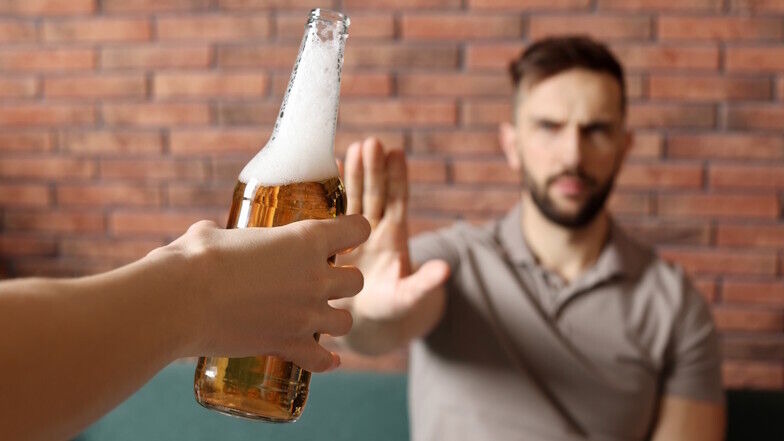 Mann lehnt angebotenes Getränk mit ausgestreckter Hand ab